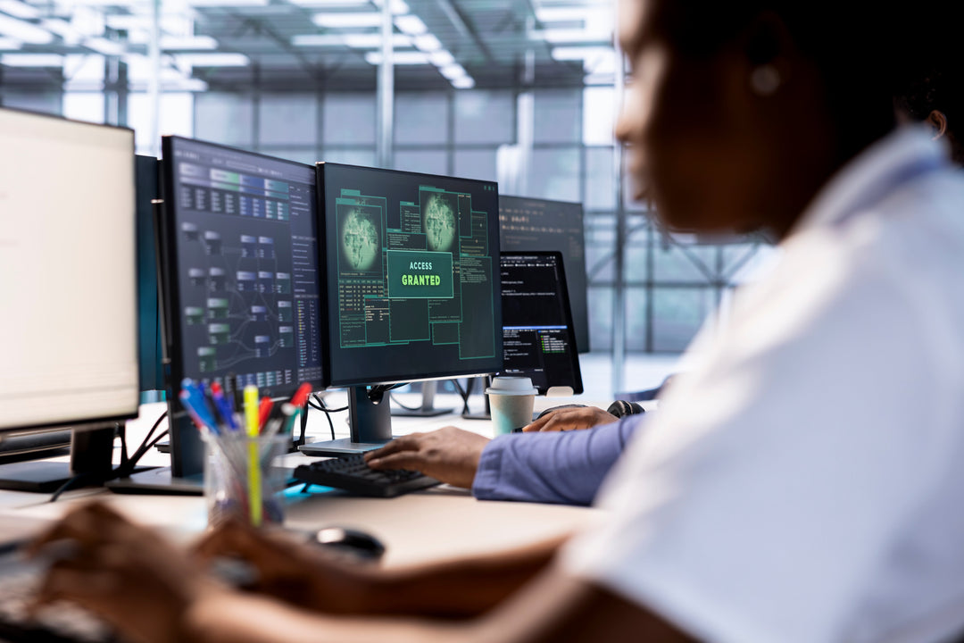 IT professional working at multiple computer monitors, with one screen displaying a green notification reading 'Access Granted' during a system configuration.